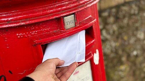 A photo of a letter being put into a letterbox